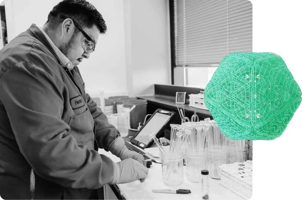 A worker with safety glasses makes notes in a laboratory